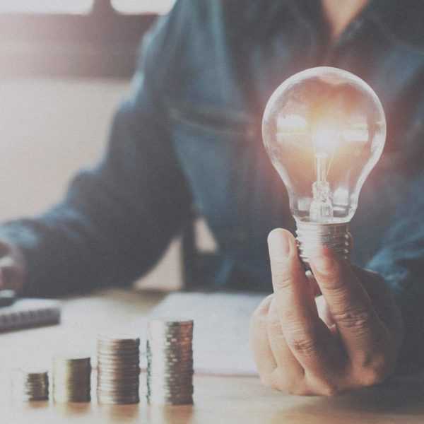 A person holding a lightbulb that is illuminated.